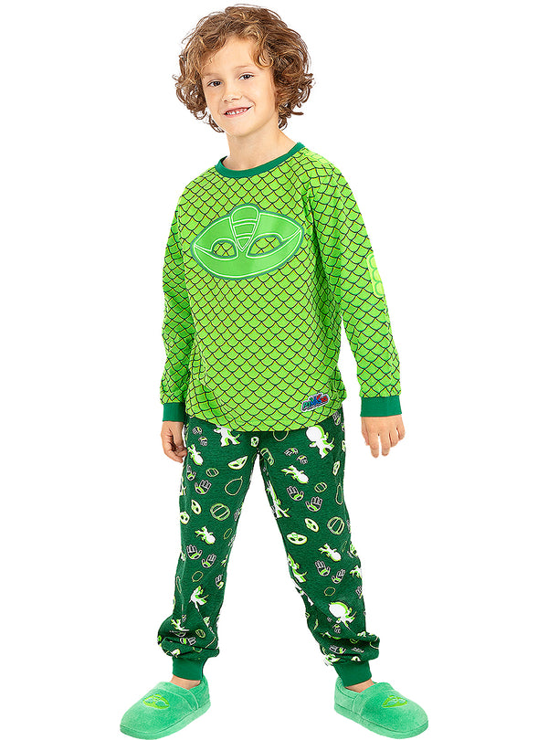 Berniukas su žalia „PJ Masks“ pižama ir šlepetėmis baltame fone.