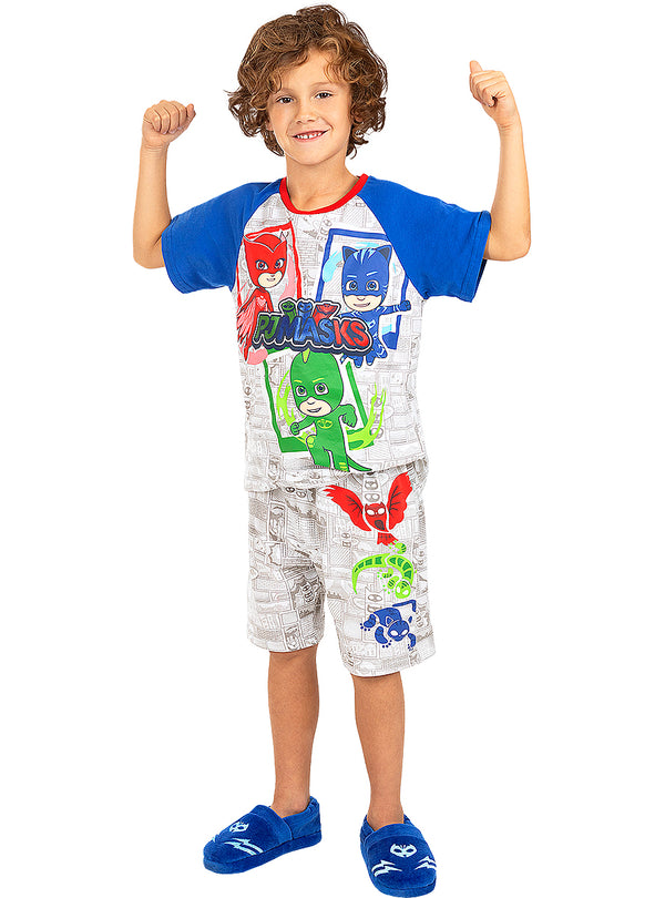 Berniukas su „PJ Masks“ pižama, mėlynomis rankovėmis ir šlepetėmis balto fono fone.