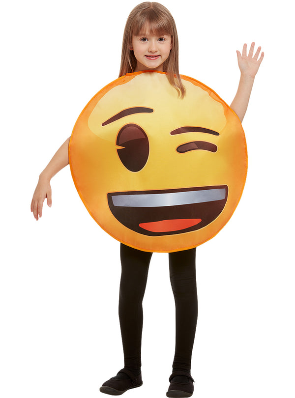 Mergaitė su geltonu mirksinčio emoji kostiumu baltame fone.