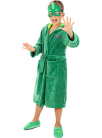 Berniukas su žaliu „PJ Masks“ chalatu, kauke ir šlepetėmis balto fone.
