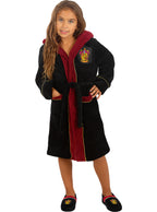 Mergaitė su juodu ir bordo spalvos „Gryffindor“ chalatu bei šlepetėmis.