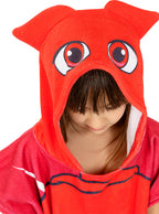 Vaikas su raudonu ponču-rankšluosčiu, turinčiu gobtuvą su ausytėmis ir didelėmis akimis.