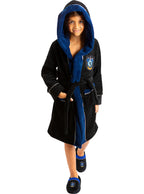 Vaikas su juodu ir mėlynu „Ravenclaw“ chalatu bei šlepetėmis balto fone.