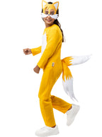 Mergaitė su geltonu „Tails“ kostiumu, kaukė ir dvi pūstos uodegos.