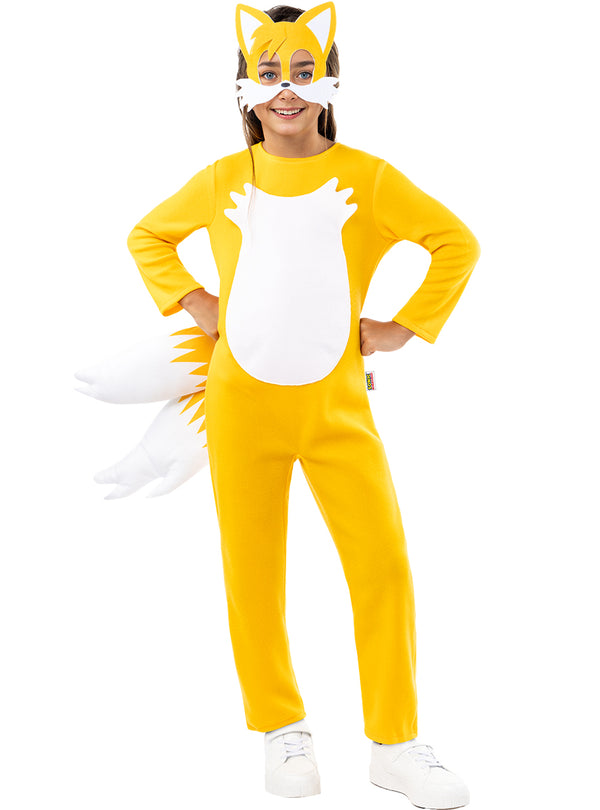Mergaitė su geltonu „Tails“ kostiumu, kauke ir dviem pūstomis uodegomis.