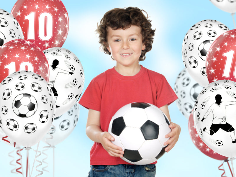 Child holding a soccer ball with soccer-themed balloons in the background