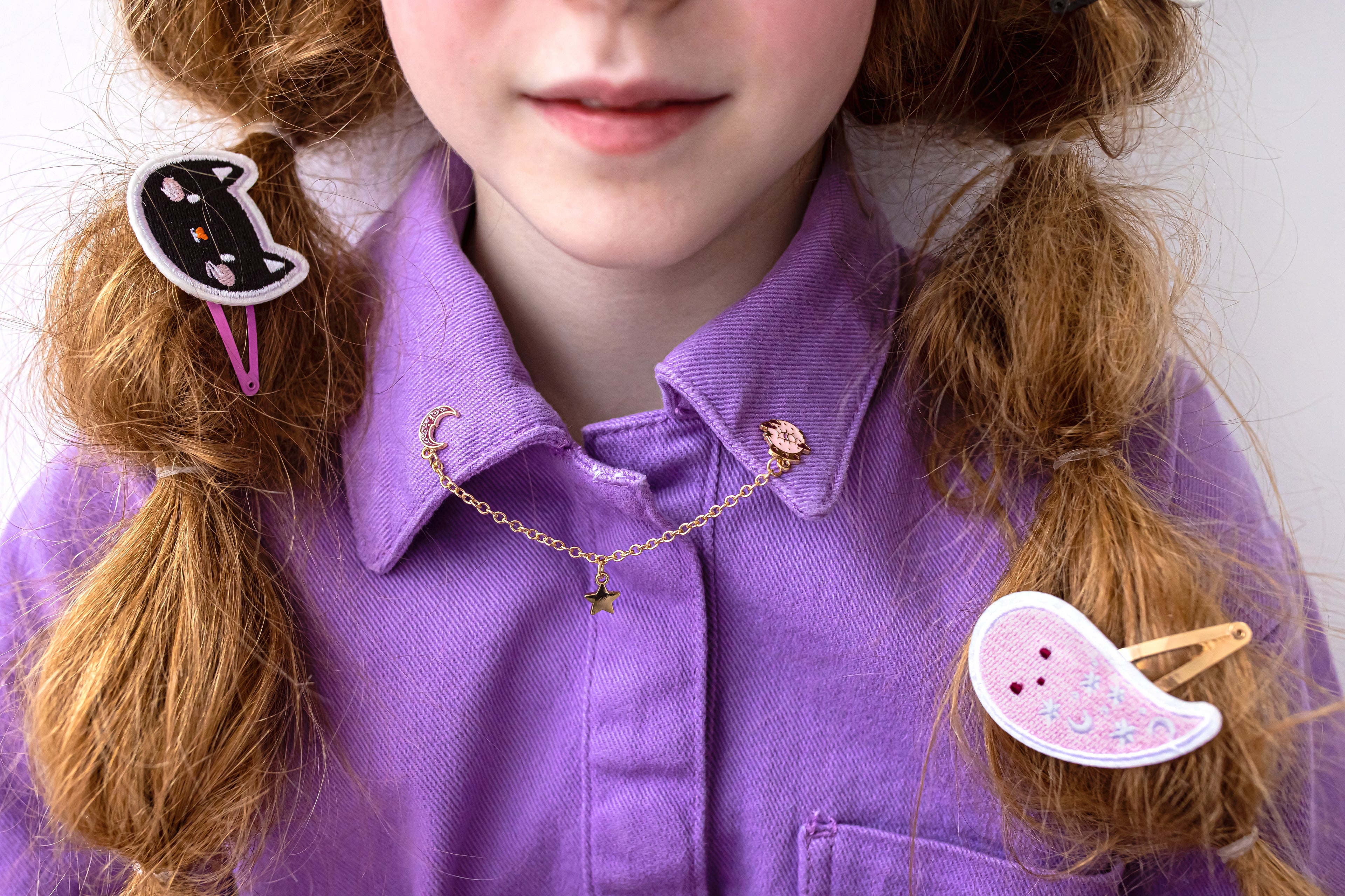 Person wearing a purple shirt with decorative hair clips on a plain background