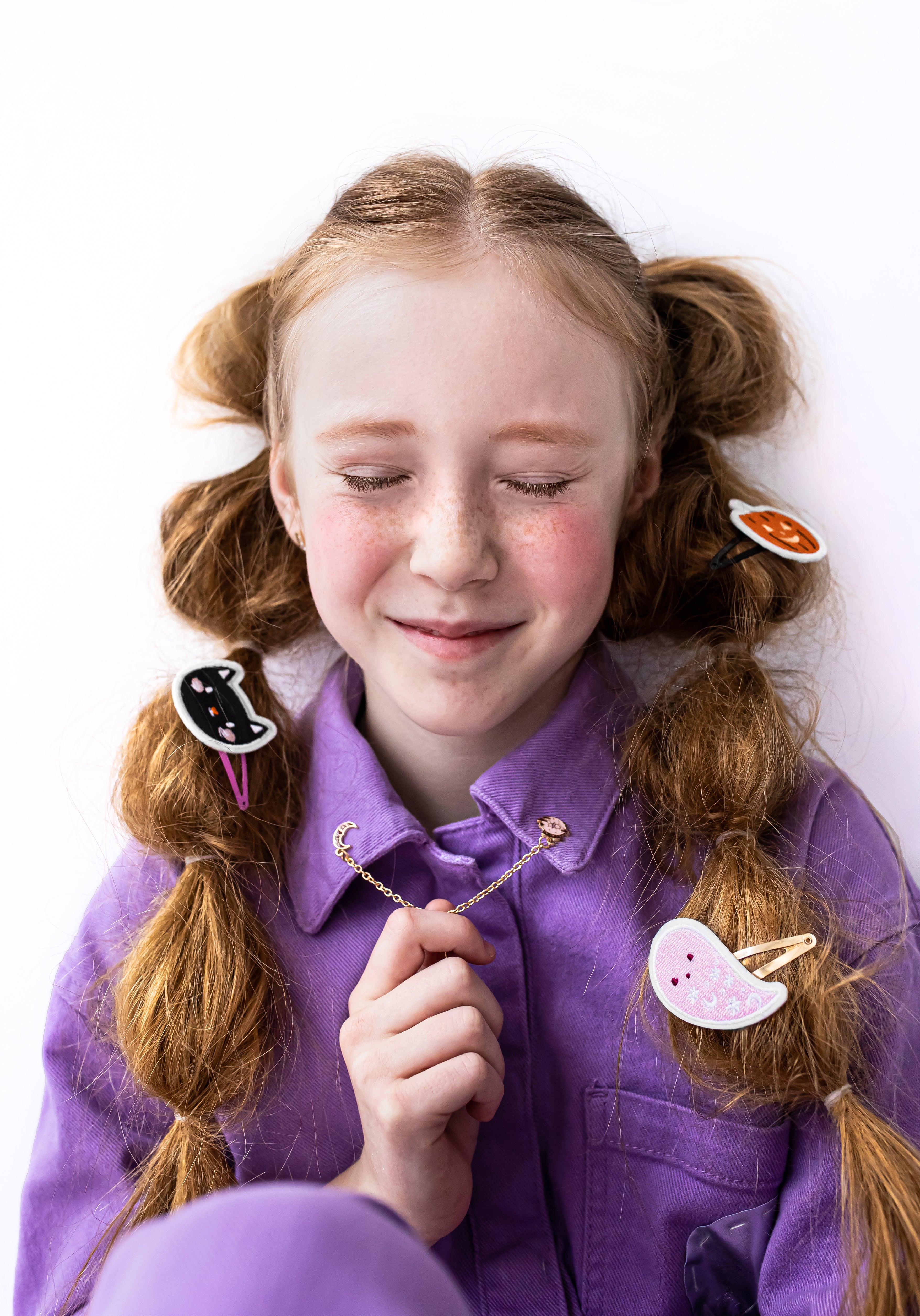 Girl with pigtails wearing colorful hair clips on a white background
