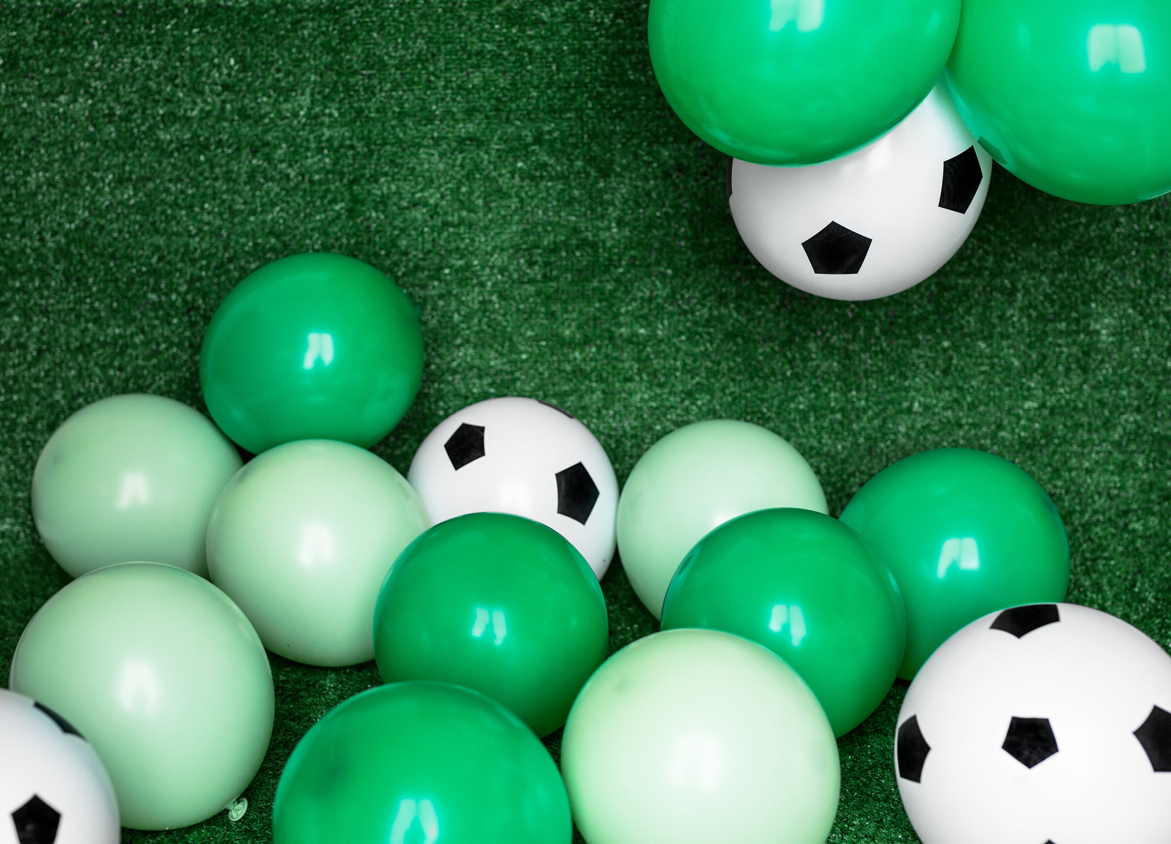 Green and white soccer balls on a green surface