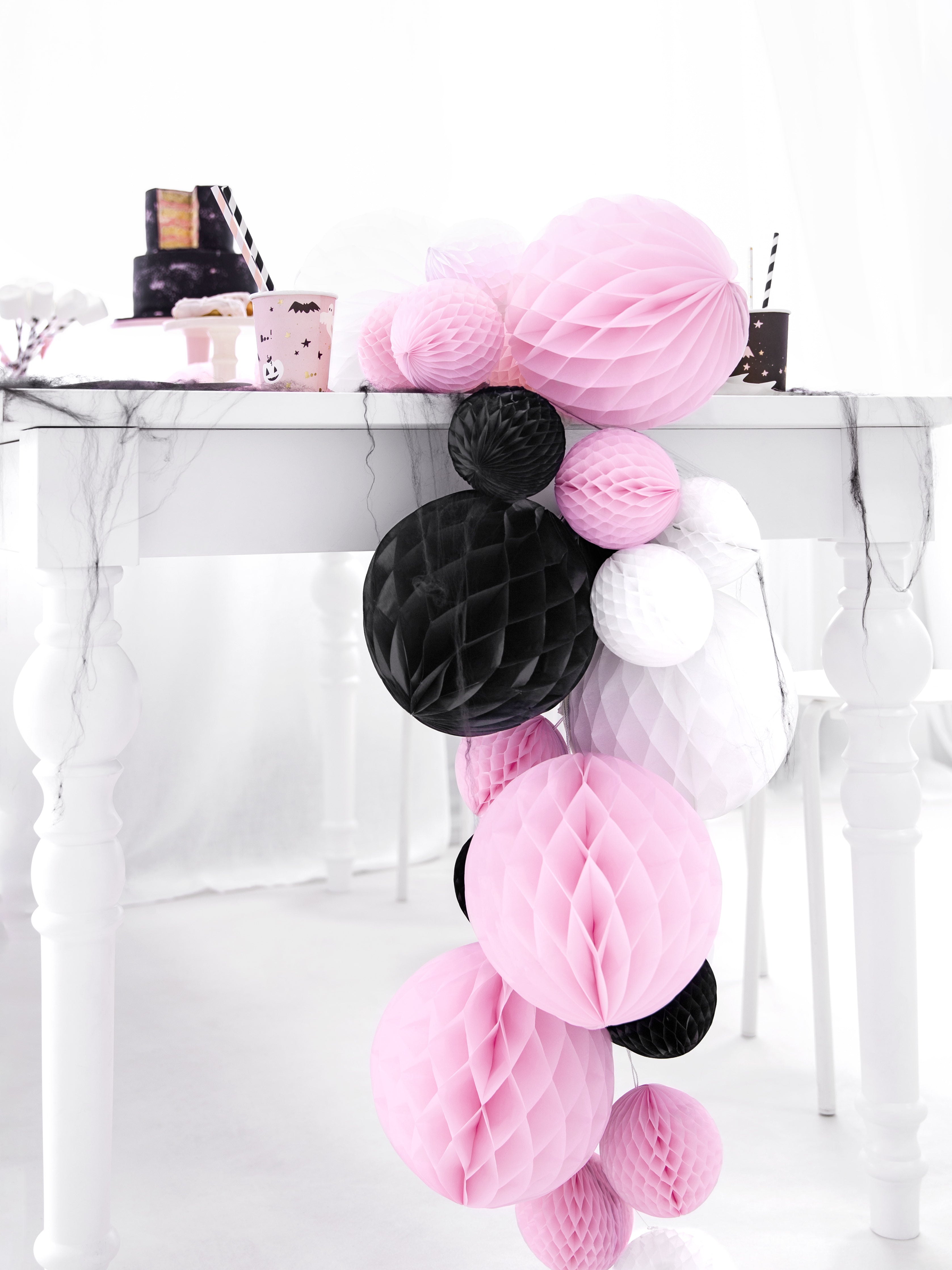 Decorative paper balls in pink, black, and white on a marble surface.