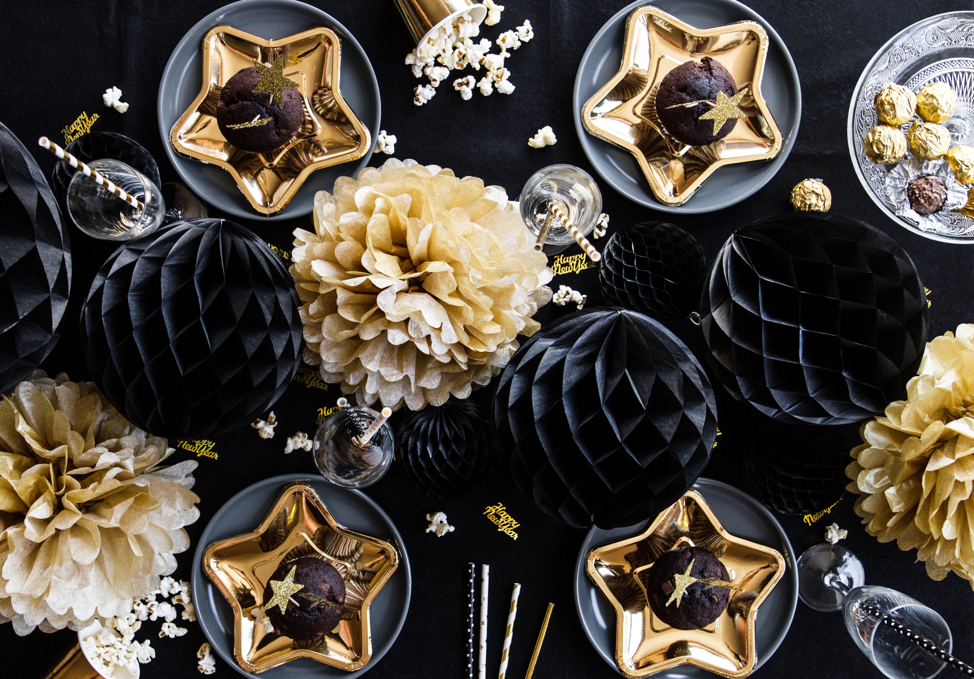 Decorative table setting with black and gold elements, including star-shaped plates and floral arrangements.