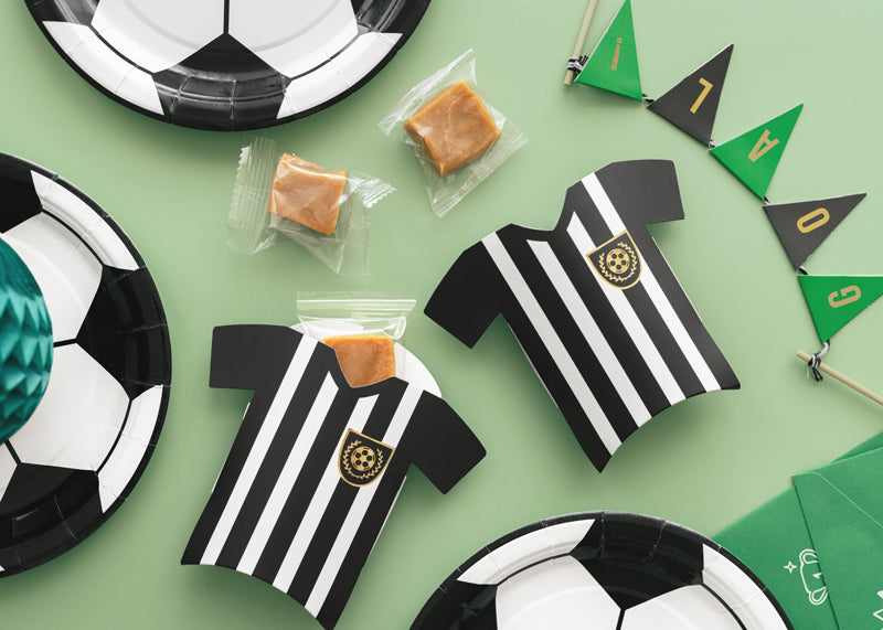 Party favors including soccer-themed plates, jerseys, and flags on a green background