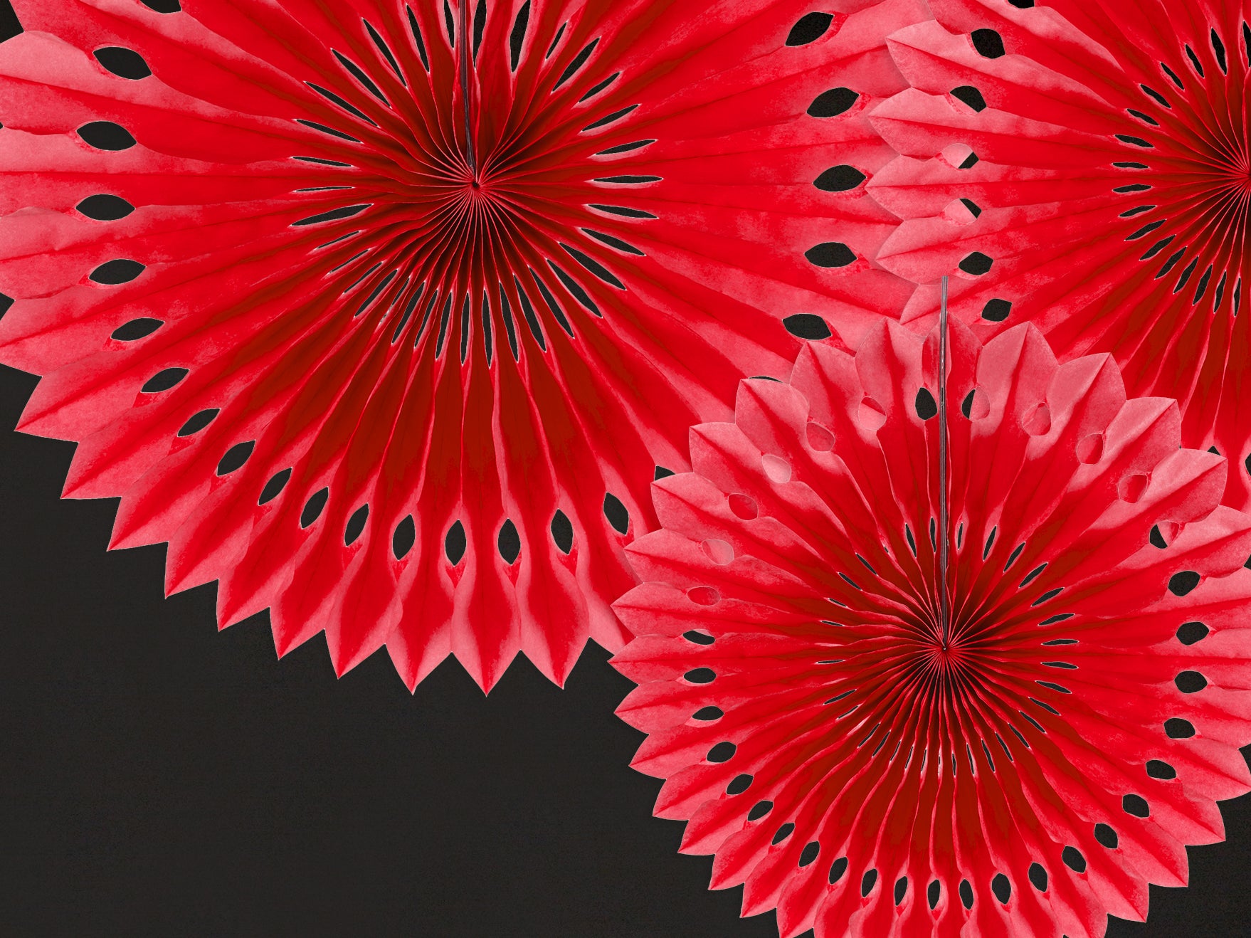 Red paper fan decorations with black dots on a black background