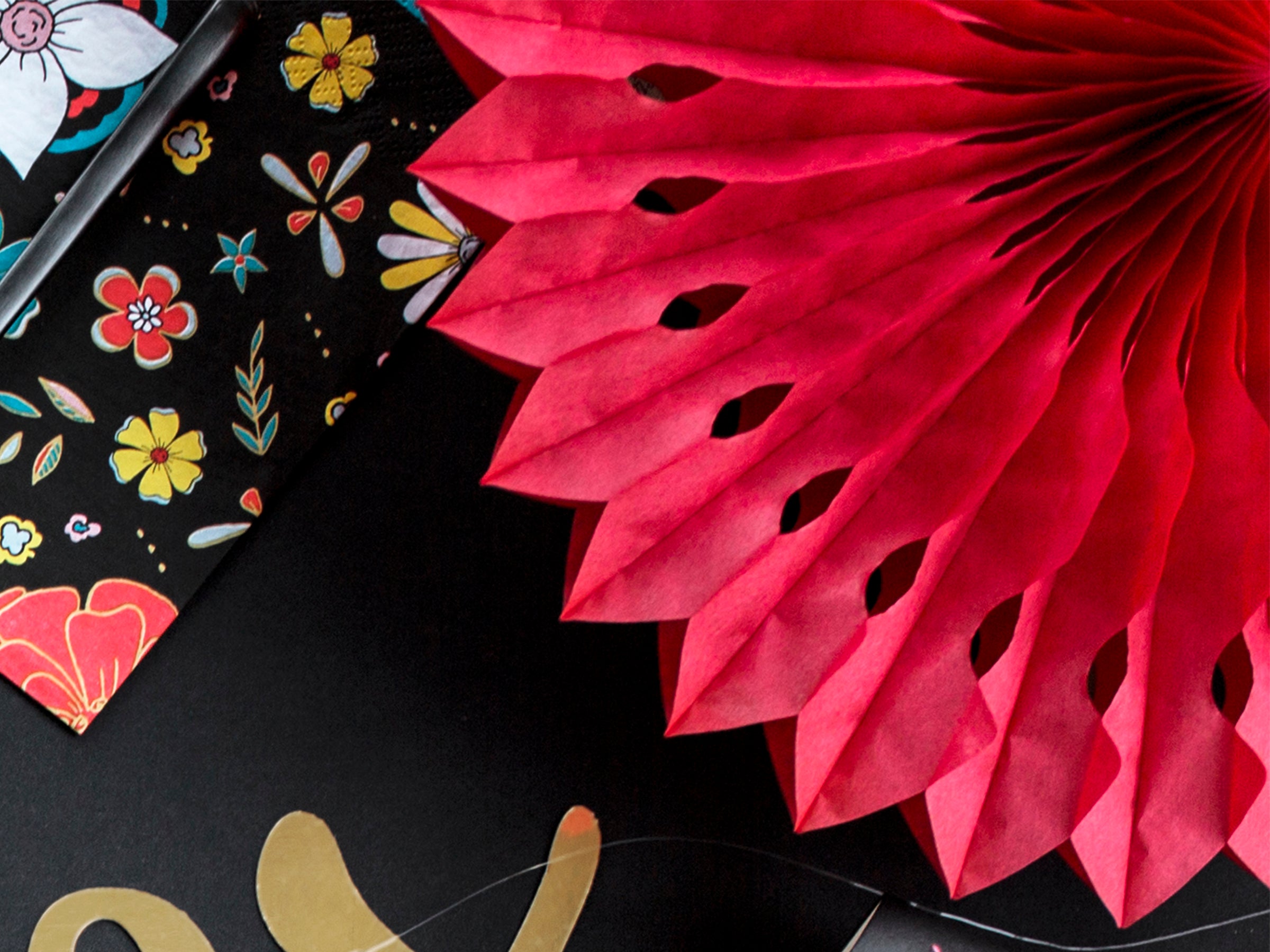 Decorative red paper fan with floral patterns on a black background