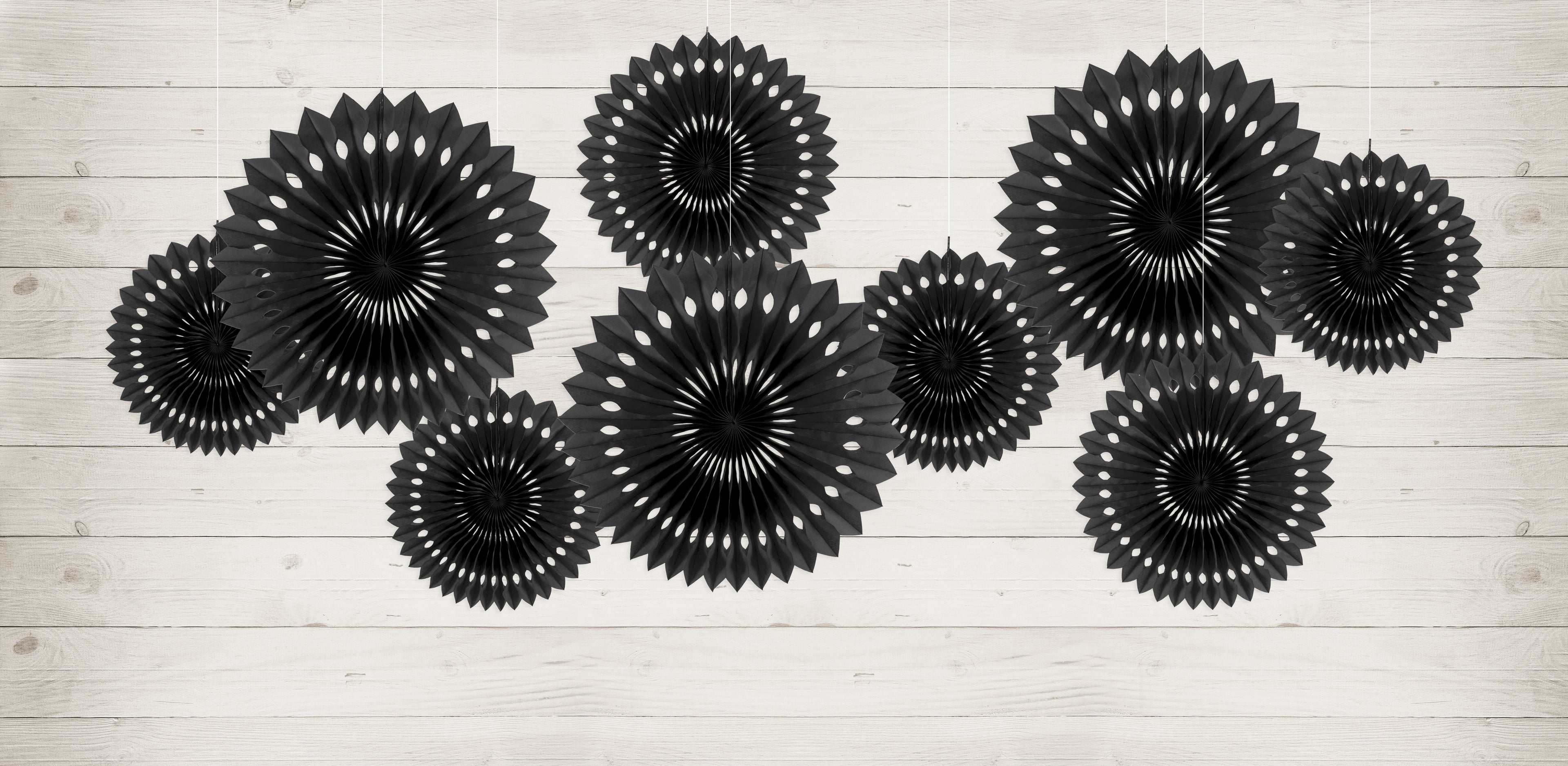 Set of black paper fan decorations on a light wooden surface