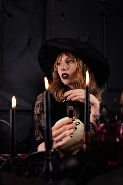 Woman in a witch costume with candles and a dark background
