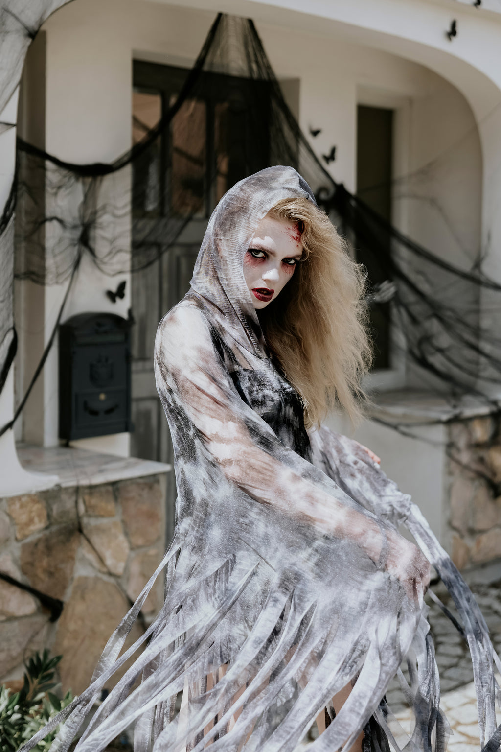 Person in a ghost costume with Halloween decorations in the background