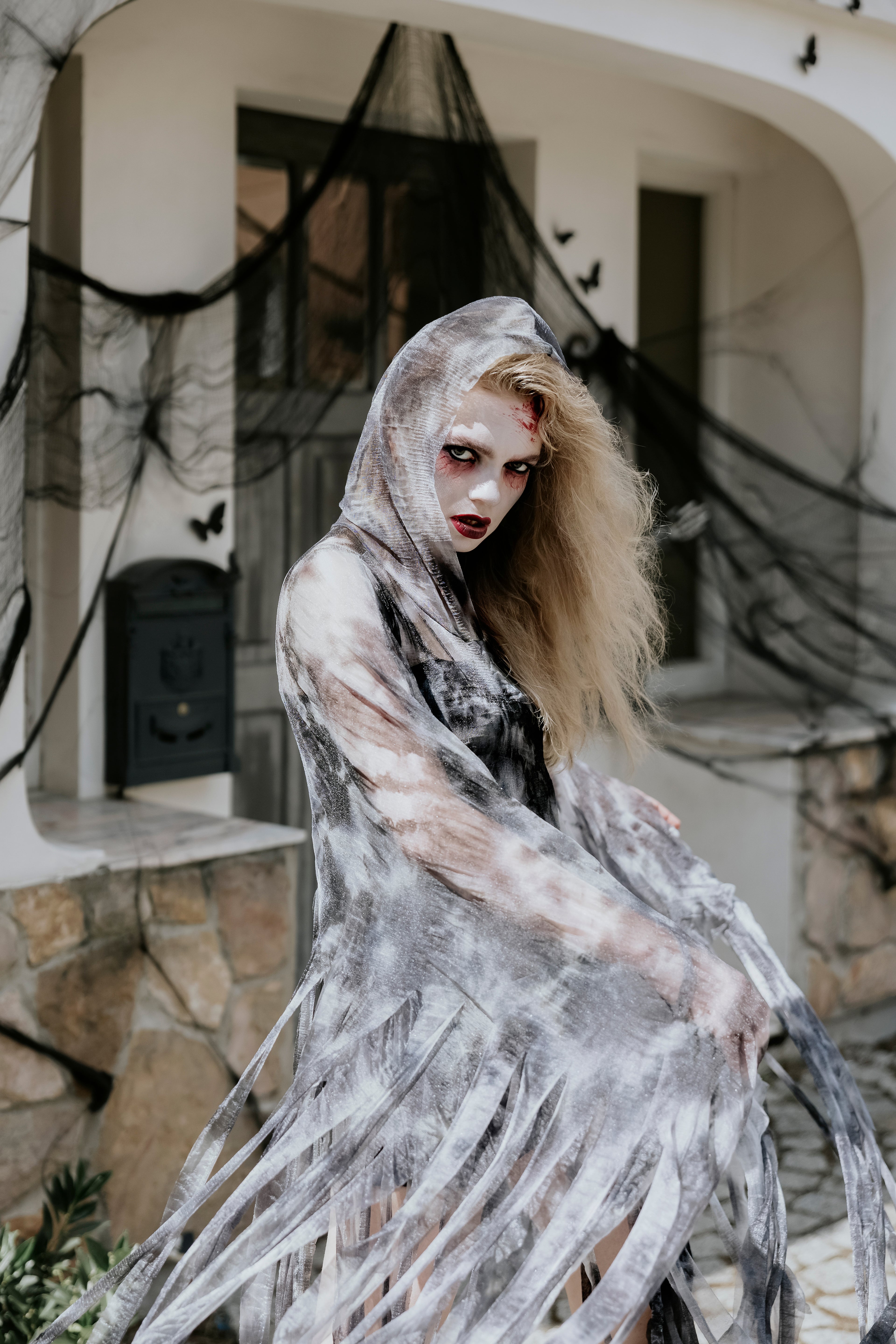 Person in a ghost costume with Halloween decorations in the background