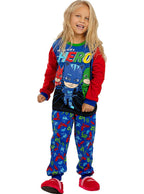 Besišypsanti mergaitė su spalvinga „PJ Masks“ pižama ir raudonomis šlepetėmis.