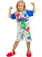 Mergaitė su „PJ Masks“ pižama ir raudonomis šlepetėmis rodo raumenis.
