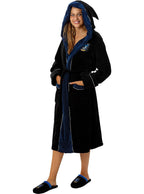 Moteris su juodu ir mėlynu „Ravenclaw“ chalatu bei šlepetėmis baltame fone.